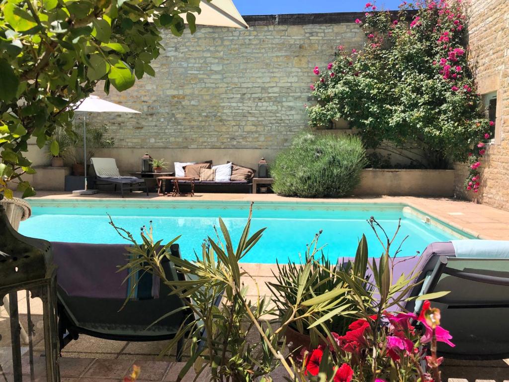 uma piscina num jardim com plantas e flores em La Cour des Délices em Gigny