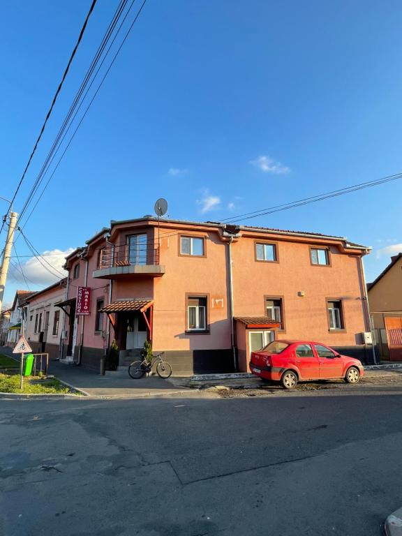 un'auto rossa parcheggiata di fronte a un edificio di Pensiunea Mario a Arad