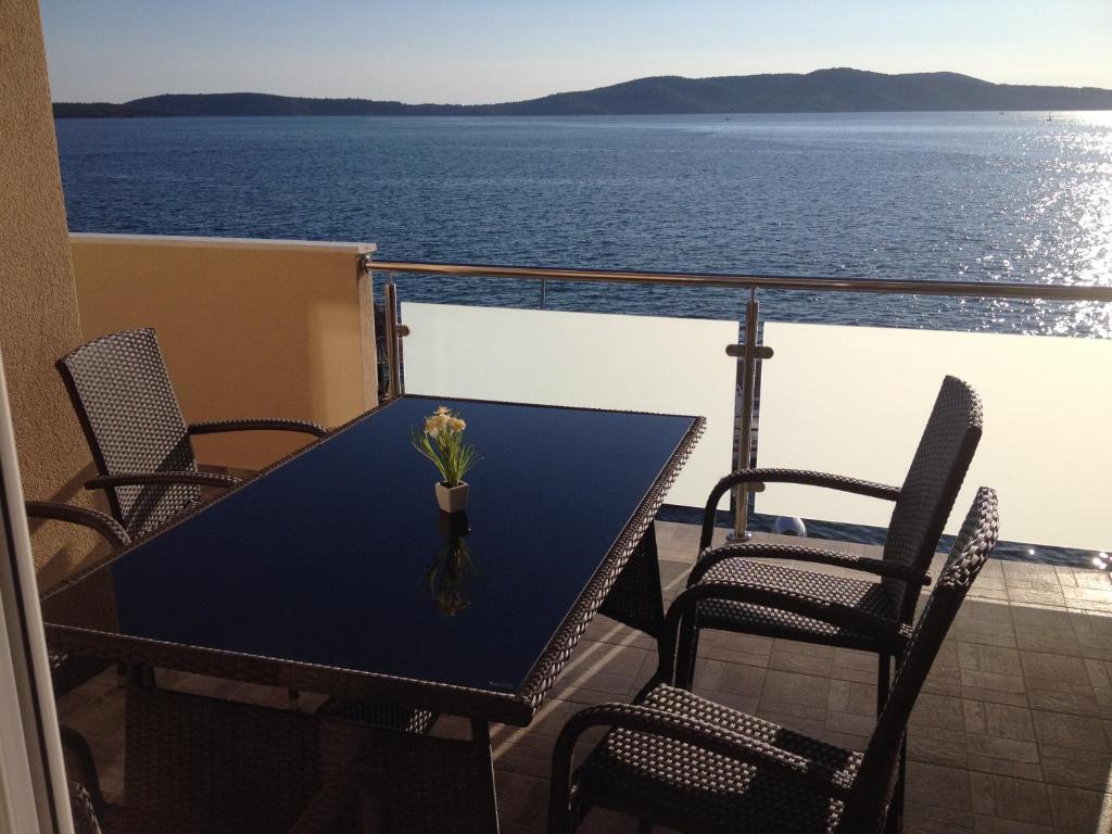 uma mesa e cadeiras numa varanda com o oceano em Apartments Šuperba em Brodarica