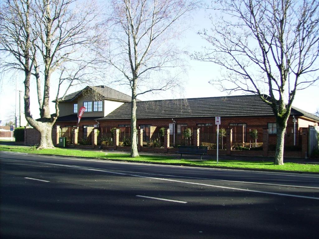 a building on the side of a street with trees at Albert Court Motor Lodge in Hamilton
