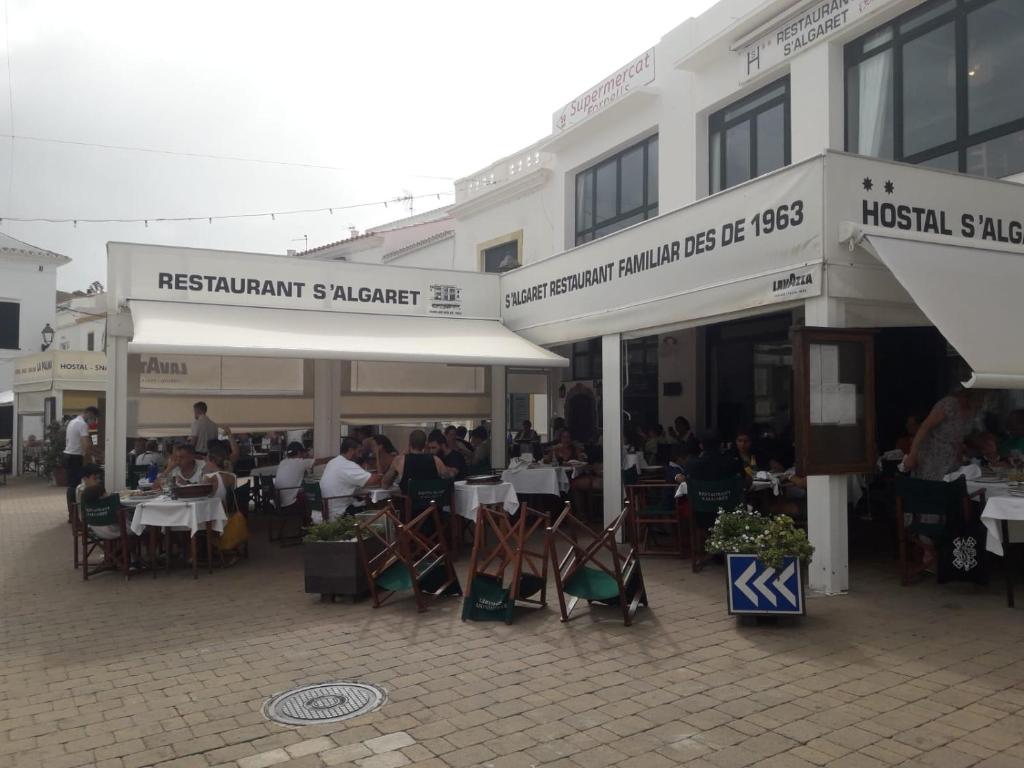 a group of people sitting at tables outside of a restaurant at Hostal S'Algaret in Fornells
