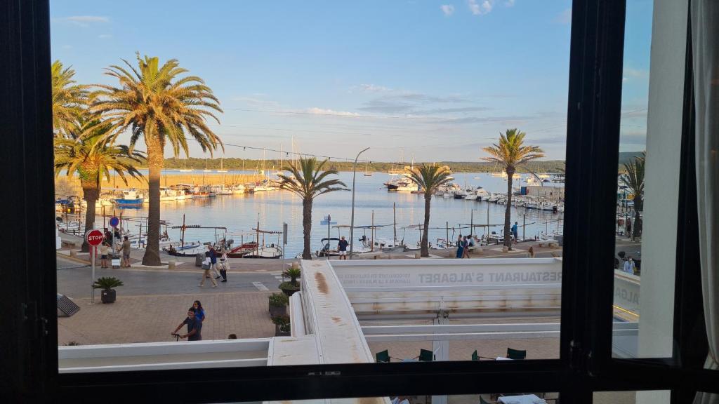 a view from a window of a marina with palm trees at Hostal S'Algaret in Fornells