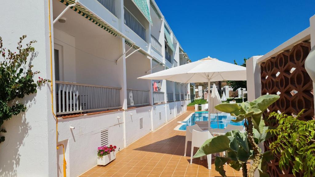 a balcony with a table and an umbrella at Hostal S'Algaret in Fornells