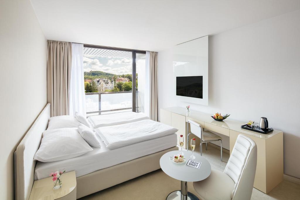 a hotel room with a bed and a desk and a window at Hotel Thermal in Karlovy Vary