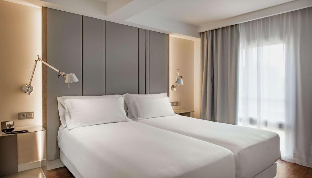 マドリードにあるNH パセオ デ ラ ハバナの窓付きの客室で、白い大型ベッド1台が備わります。