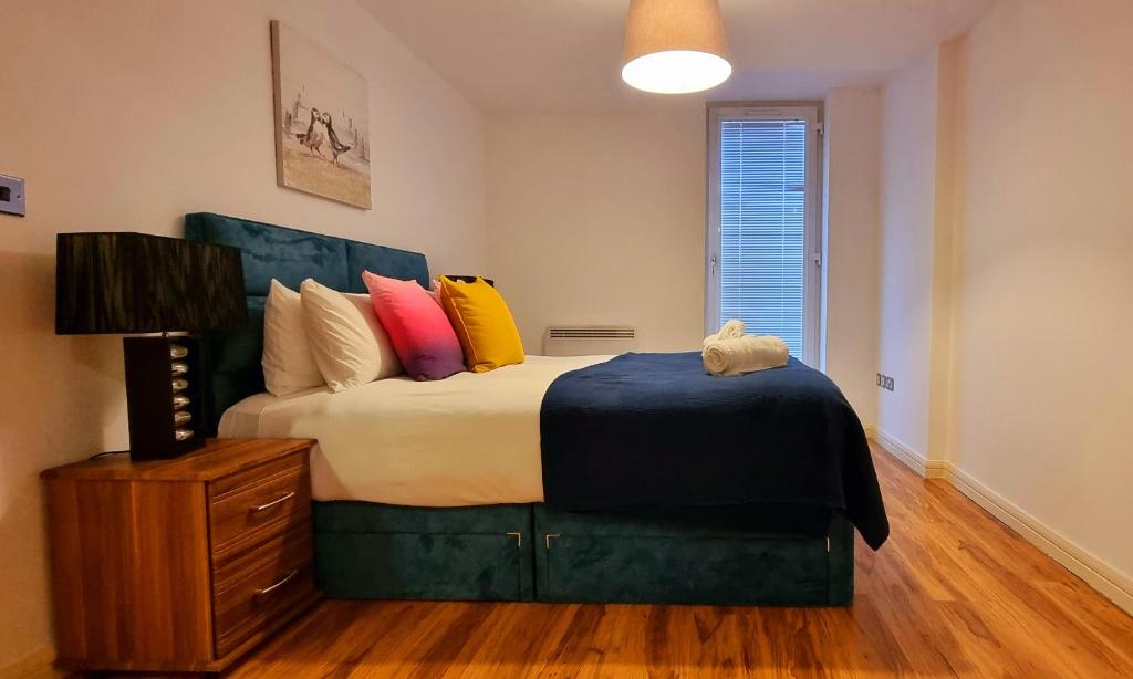 - une chambre avec un grand lit et des oreillers colorés dans l'établissement StayBrum Acadian City Centre Apartments Birmingham Chinatown, à Birmingham