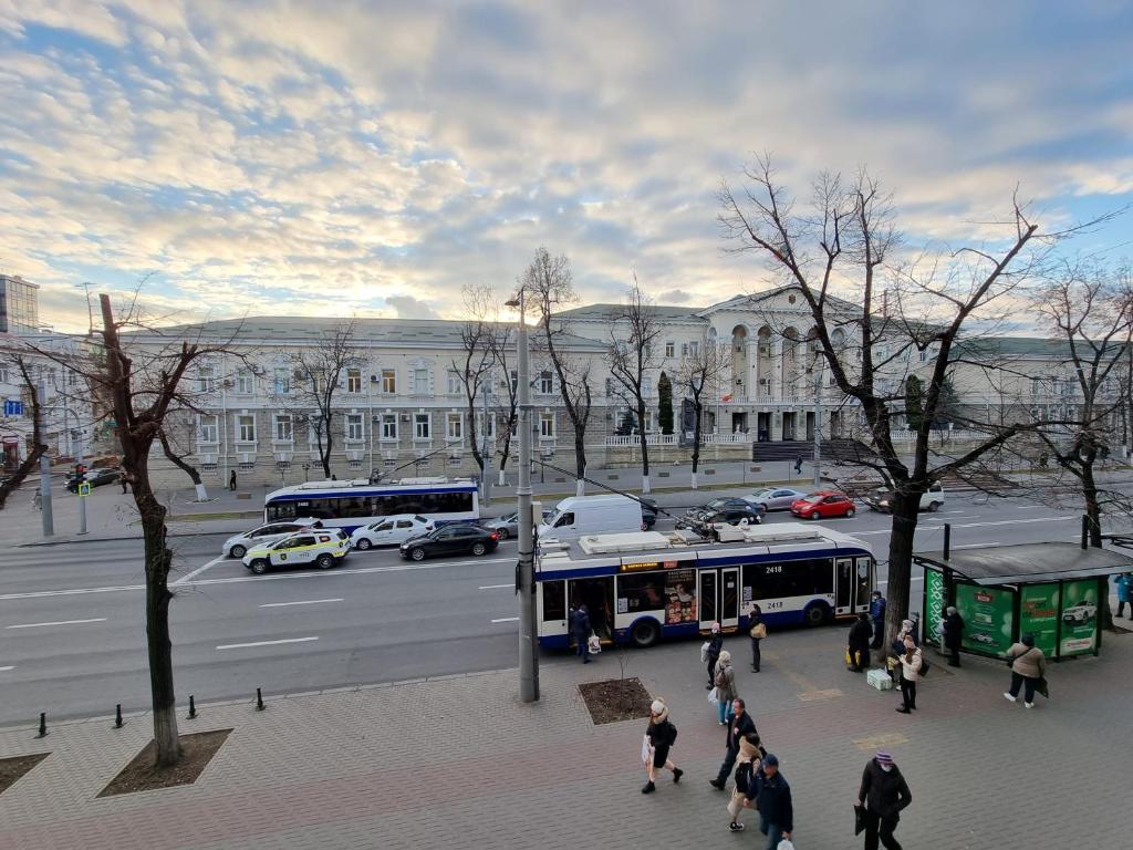 Grand Ultracentral Apartments Stefan cel Mare in the heart of Chisinau في كيشيناو: مجموعة من الناس يمشون على الرصيف بالقرب من الحافلة