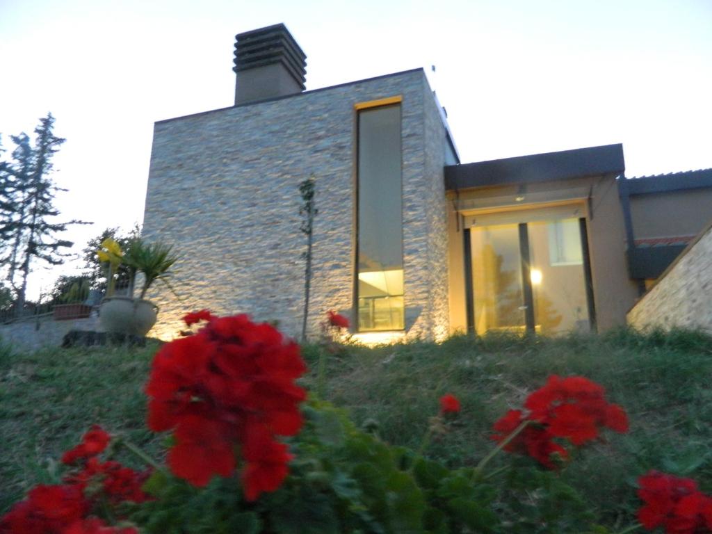 una casa con fiori rossi davanti di Il Poggetto Moon Light Home Stay ad Arezzo
