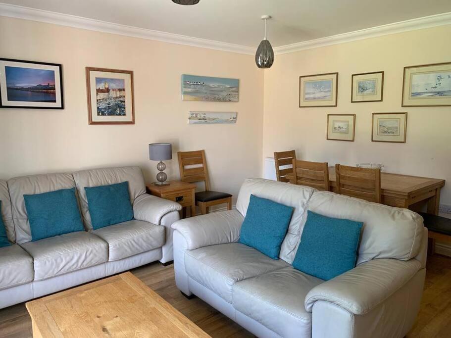 een woonkamer met 2 banken en een tafel bij Cheerful 3 bedroom home close to beach and High St in Sheringham