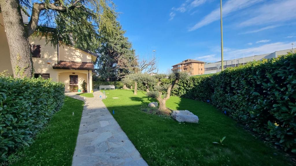 ein grüner Hof mit einem Baum und einem Gebäude in der Unterkunft B&B Villa Eden in Vimercate