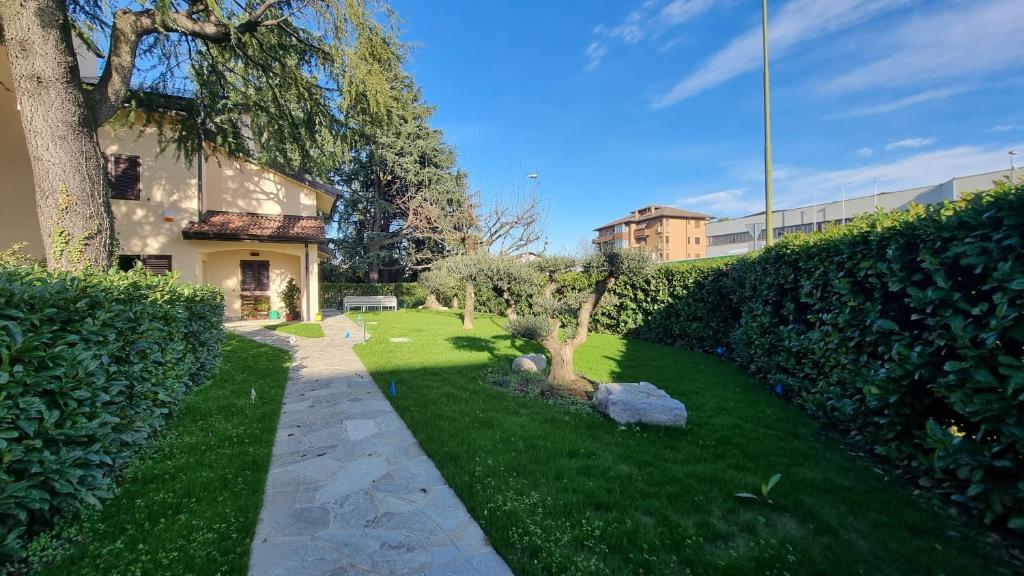 a green yard with a tree and a building at B&B Villa Eden in Vimercate