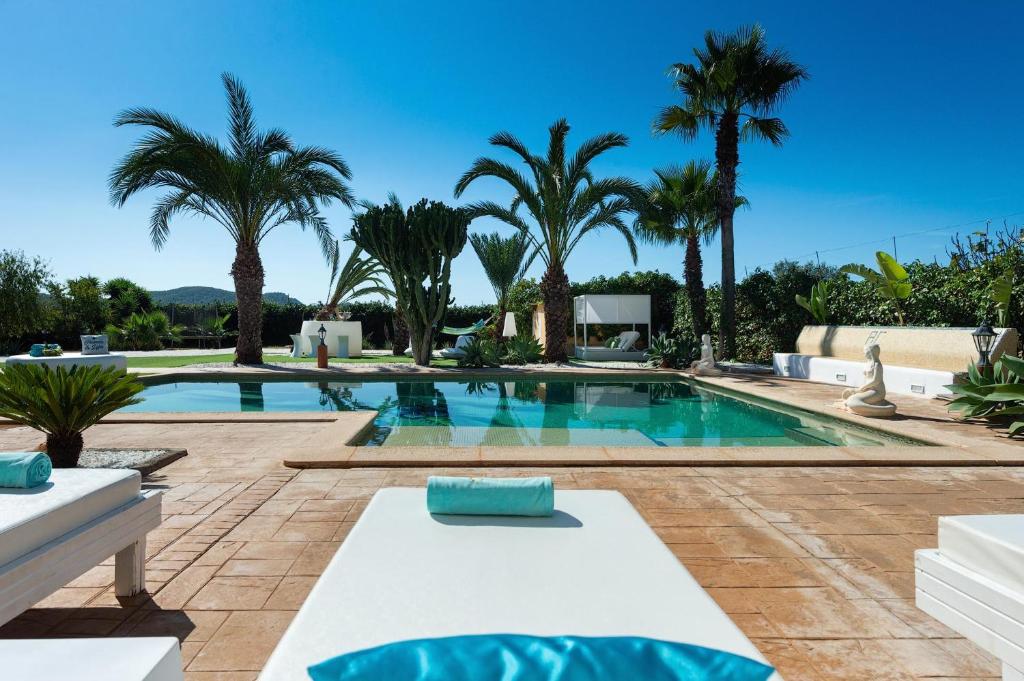 a swimming pool with palm trees and a villa at Serena Villa in Ibiza Town
