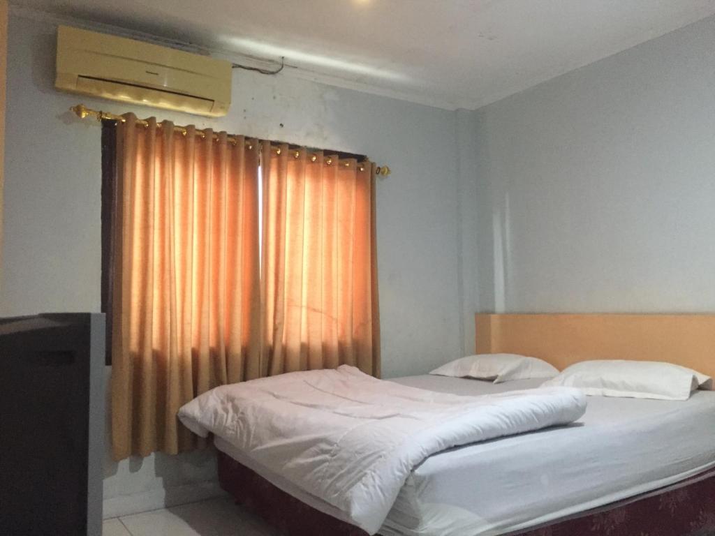 a bedroom with a bed and a window with avertisement at Losmen PUM Syariah at Desa Wisata Sabang in Sabong