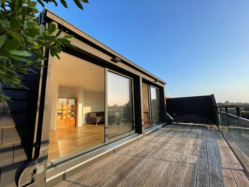 a house with a large deck with glass windows at La Maison Rouge in Steenwerck