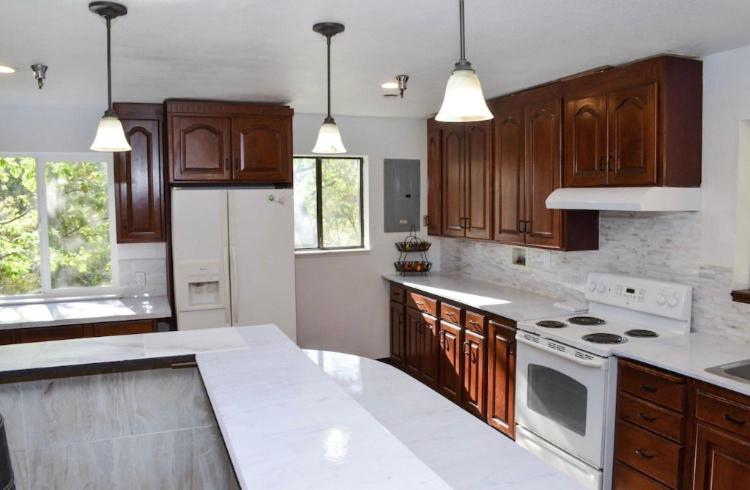 a large kitchen with wooden cabinets and white appliances at Forest Cottage Large Group Destination Vacation Sleeps 45 in Foresthill