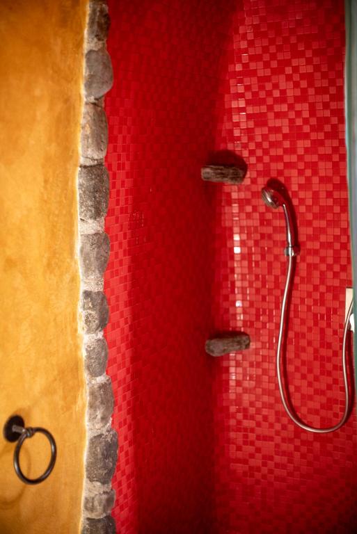 a shower with a red wall with a shower head at Villa Orpheus Santorini in Megalokhori