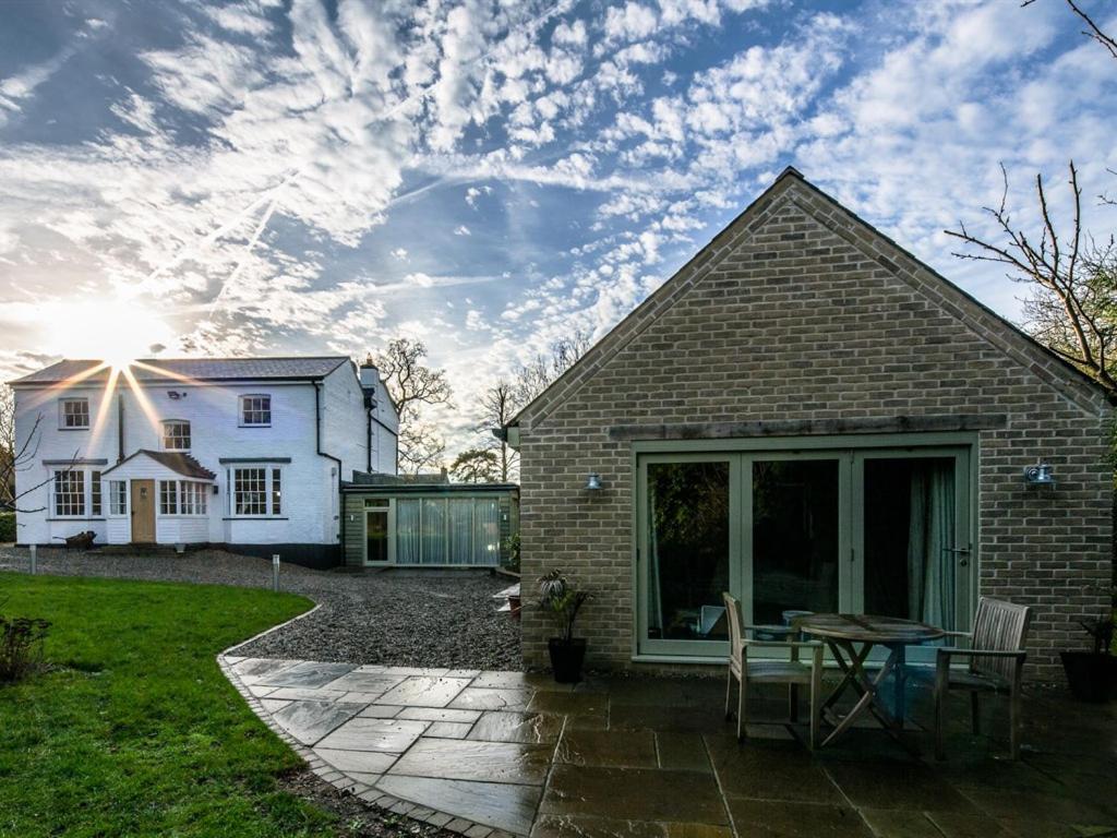 a house with a patio with a table and chairs at Eagle Mill Luxury Rooms in Huntingdon