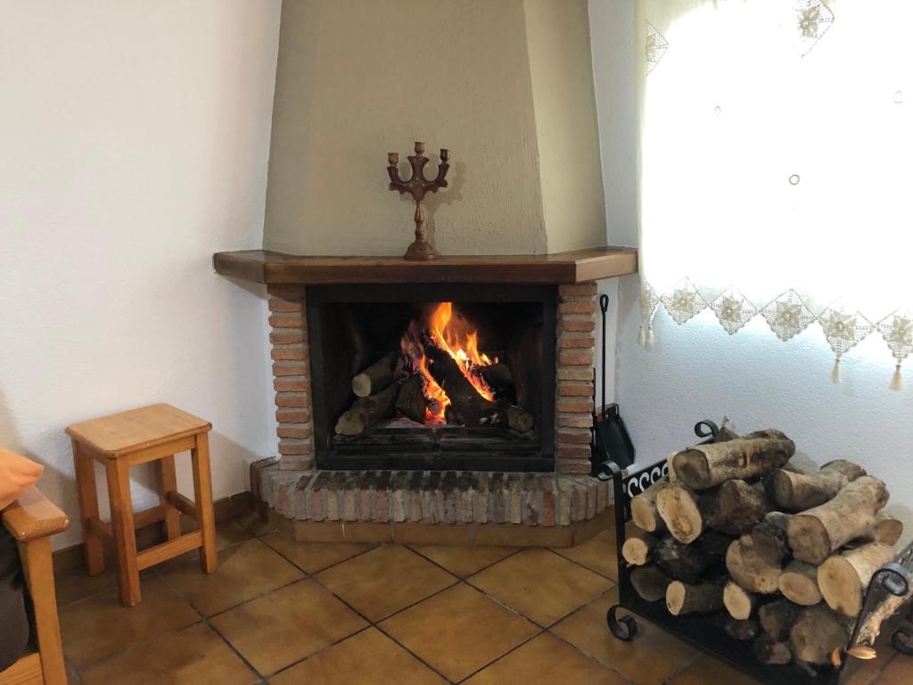 a living room with a fireplace with a pile of logs at Alojamiento Noe in Arroyo Frio