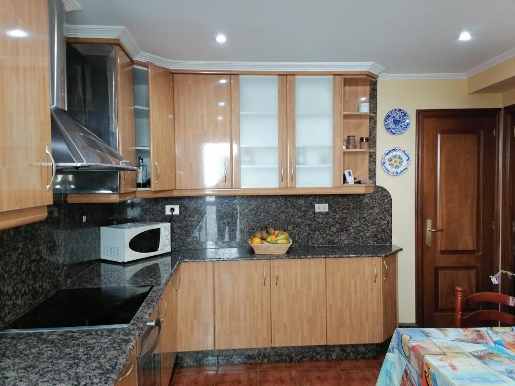 a kitchen with wooden cabinets and a bowl of fruit on the counter at PISO EN PLENO CENTRO DE MIÑO in Miño