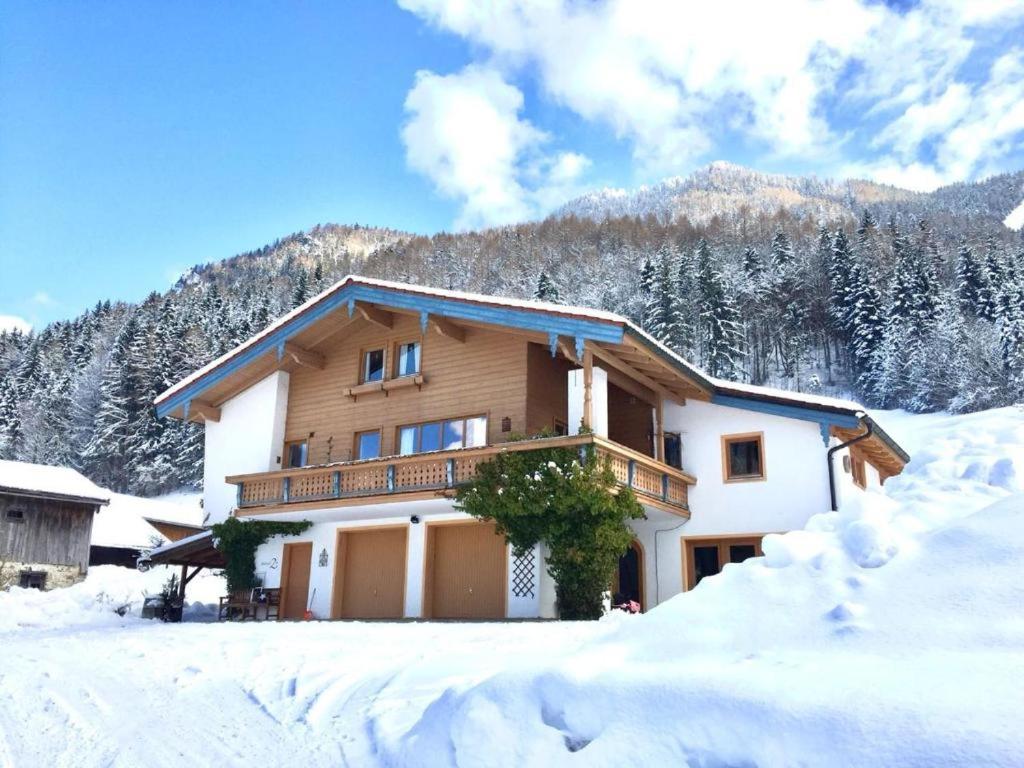 a house in the snow with mountains in the background at Staller Hof inkl. Chiemgaukarte in Ruhpolding