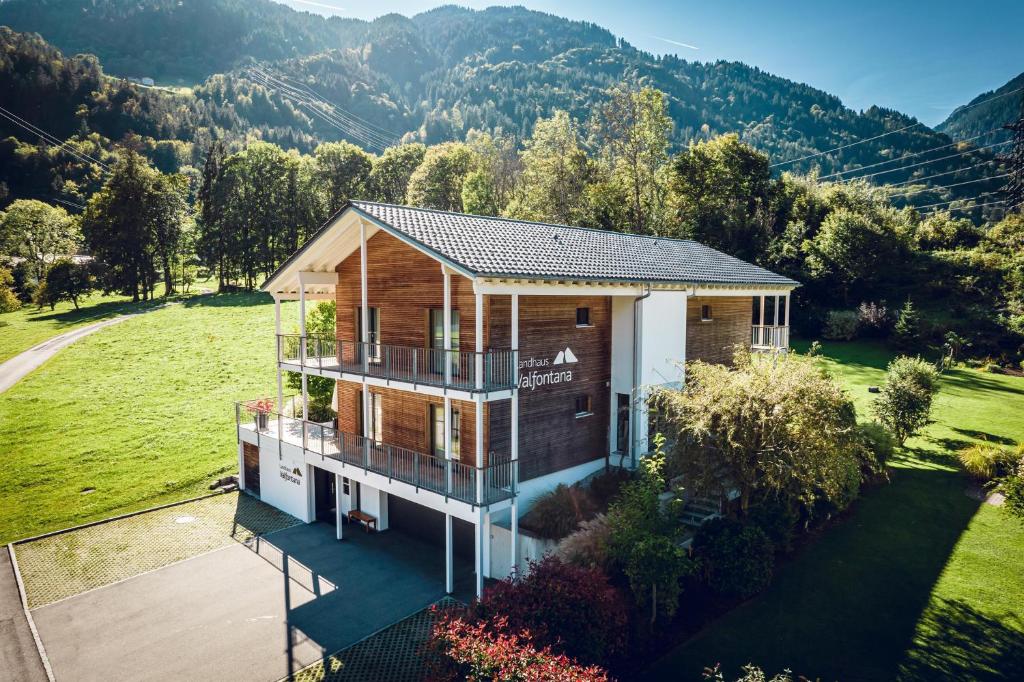 une vue aérienne sur une maison avec des montagnes en arrière-plan dans l'établissement Landhaus Valfontana, à Vandans