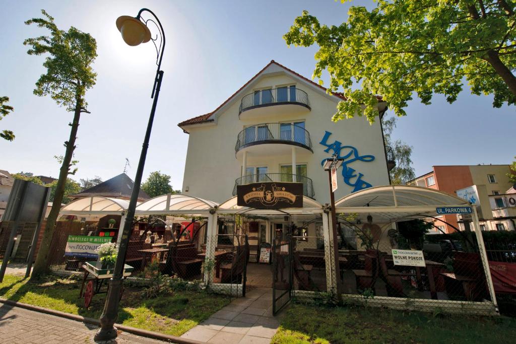 a building with tables and umbrellas in front of it at Pensjonat Lazur in Mielno
