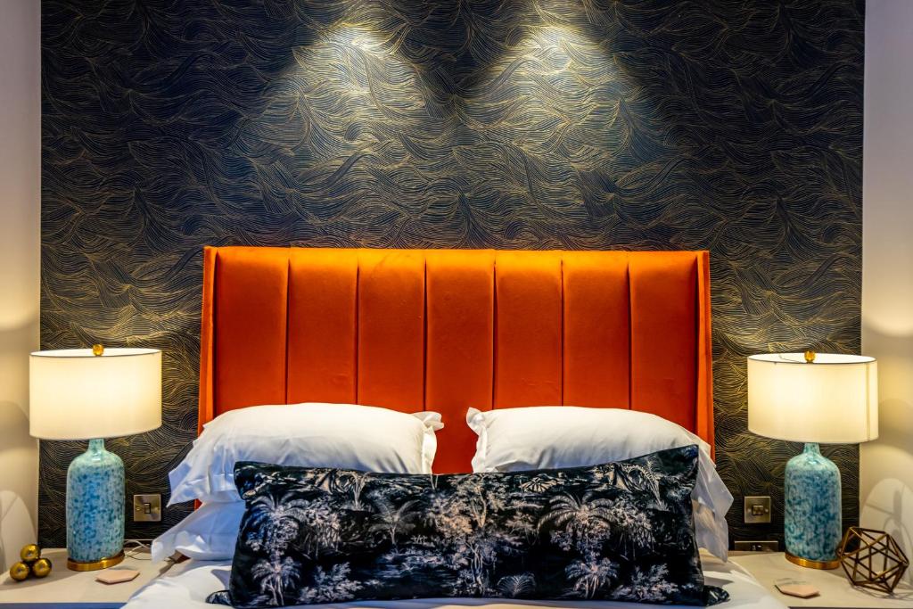 a bed with an orange headboard next to two lamps at Twenty Seven HQ in York