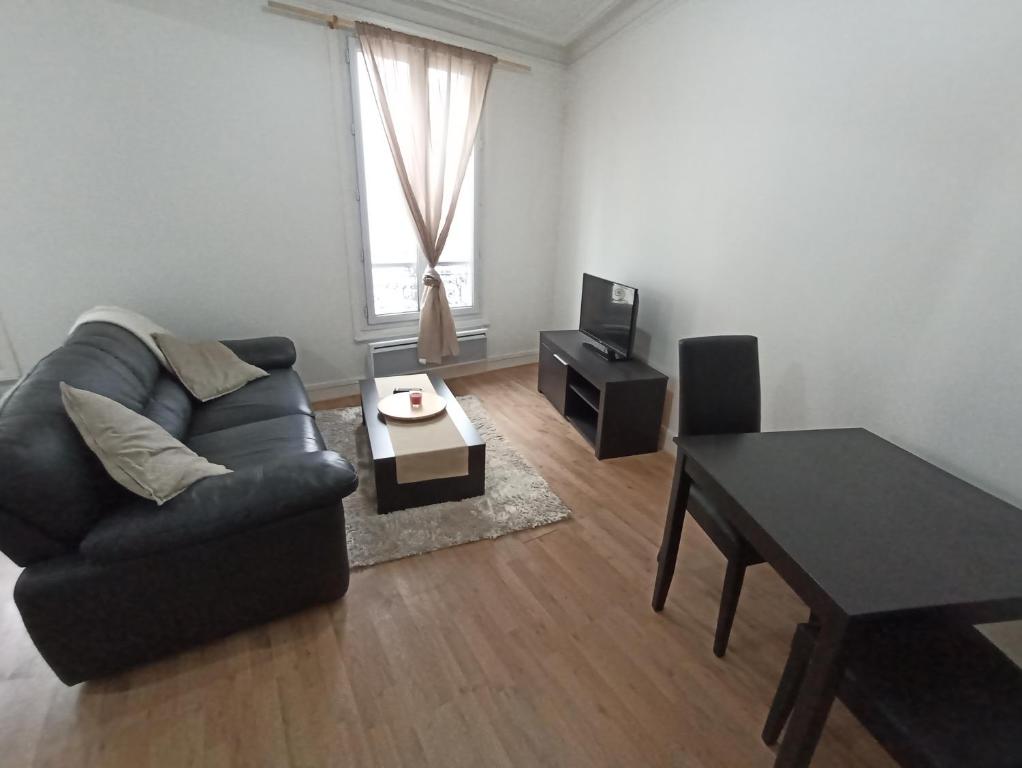 ein Wohnzimmer mit einem Sofa und einem Tisch in der Unterkunft Beautiful appartement, 20 min to Champs-Elysées in Maisons-Laffitte