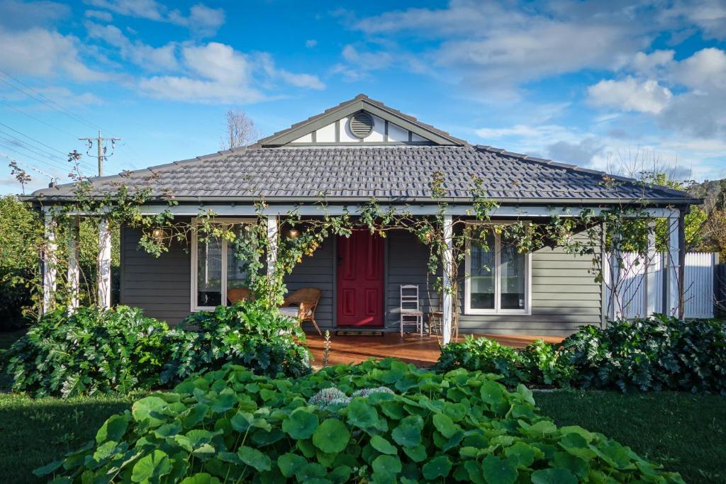 una casa con una puerta roja y un jardín en Pomegranate Guest House, en Healesville