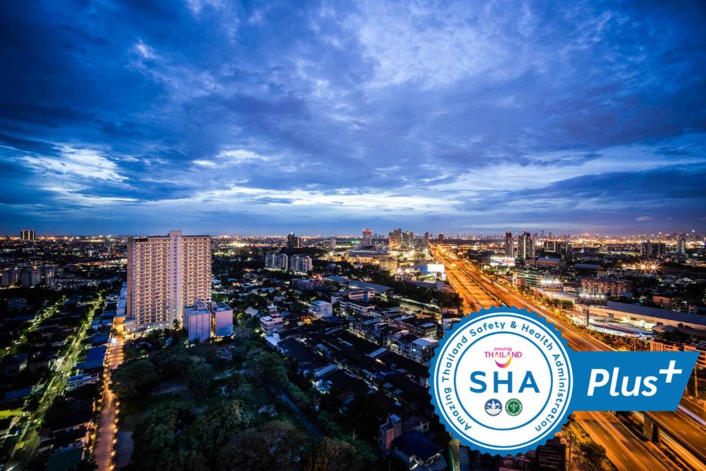una vista de la ciudad por la noche con una señal shha plus en Avana Hotel and Convention Centre SHA Extra Plus en Bangkok