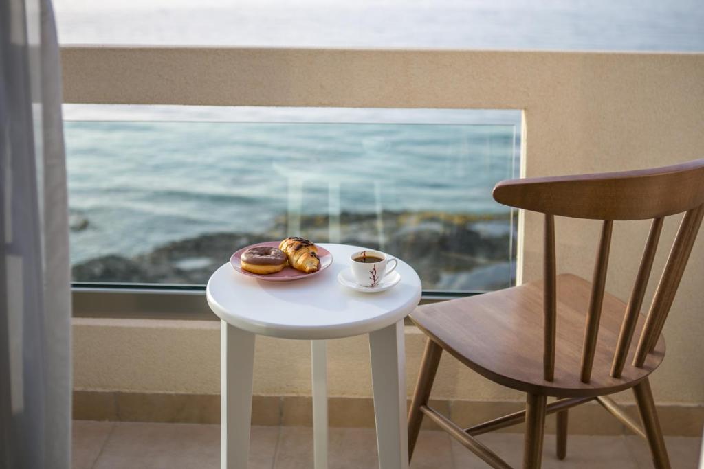 einen Tisch mit einem Teller Donuts und einem Stuhl in der Unterkunft Almyra Seaside House Mochlos in Mochlos