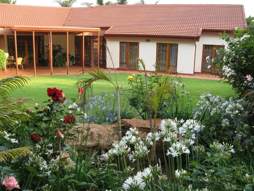un jardín con flores frente a una casa en Touraco Guesthouse, en Pretoria