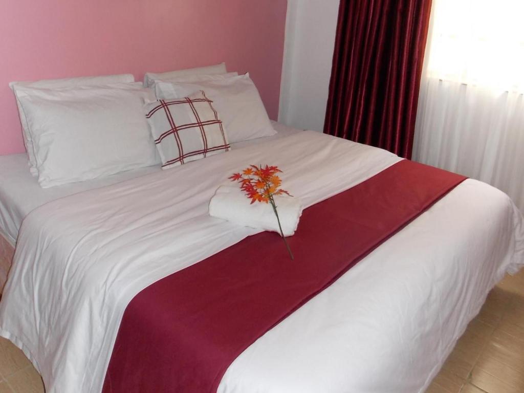 a white bed with a flower on top of it at Baraka Home in Nairobi