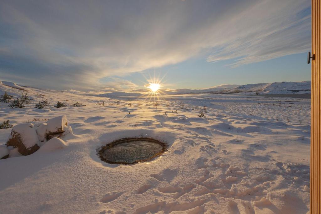 a hole in the snow with the sun in the background at Iceland Lakeview Retreat in Selfoss