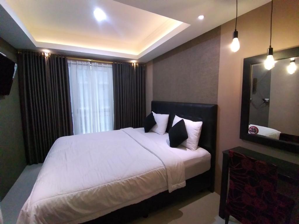 a bedroom with a large bed with white sheets and pillows at Apartement Grand Asia Afrika Bandung by House Of Tofi in Bandung