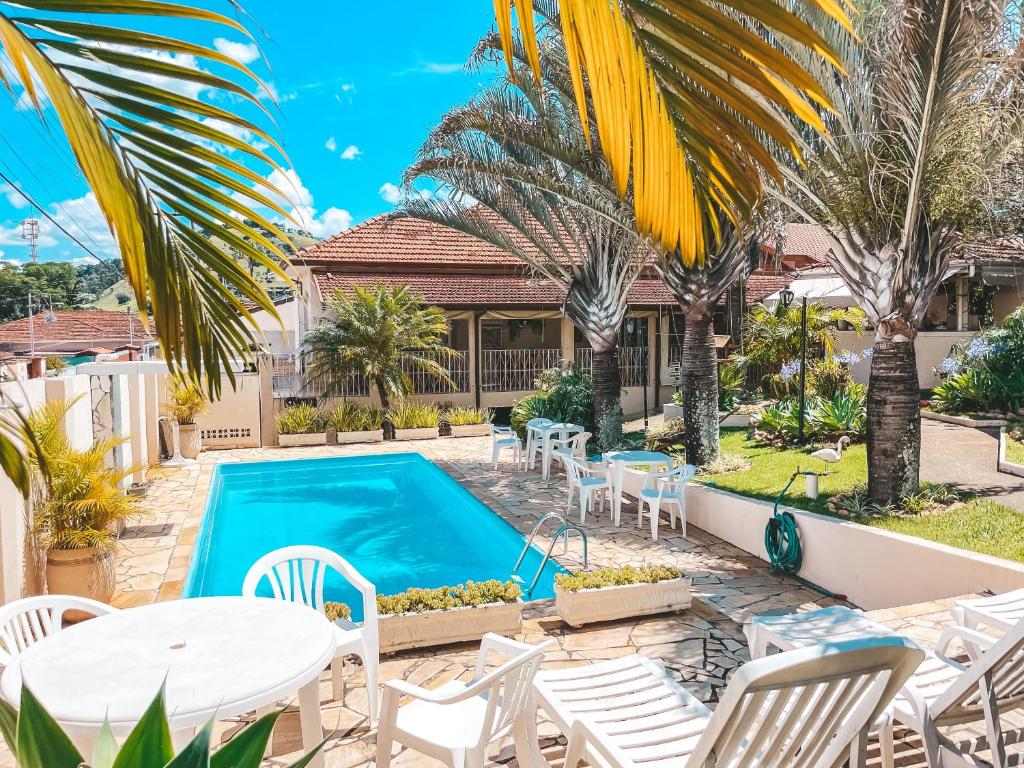 a villa with a swimming pool and palm trees at Pousada Quinta dos Colibris in São Bento do Sapucaí