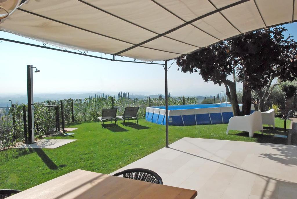 un patio con mesa y sillas bajo una sombrilla blanca en BELVEDERE CERIEL, en Cavaion Veronese