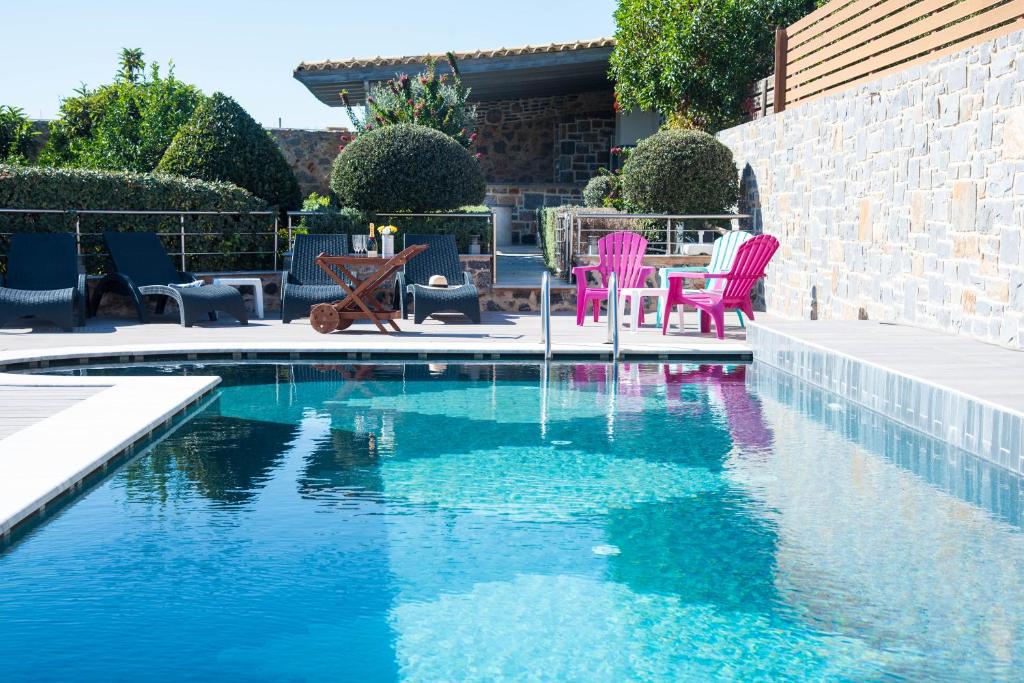 een zwembad met roze stoelen en een tafel bij Nina Villa Cretevasion in Anópolis