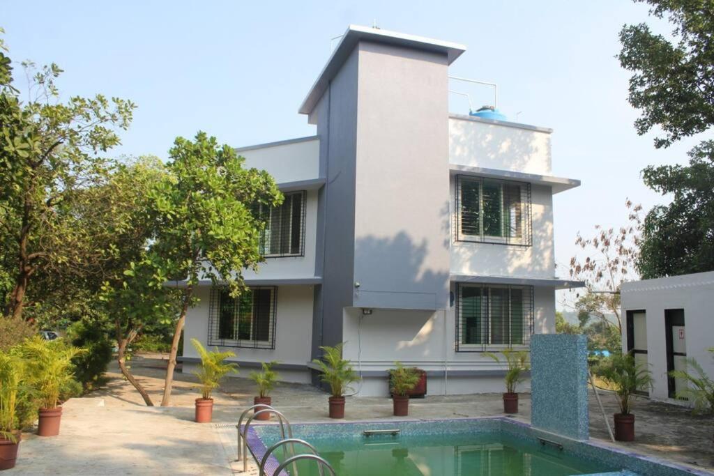 a house with a swimming pool in front of a building at Ivy Maitri Farm 3 Bhk with Private Pool - Badlapur in Badlapur