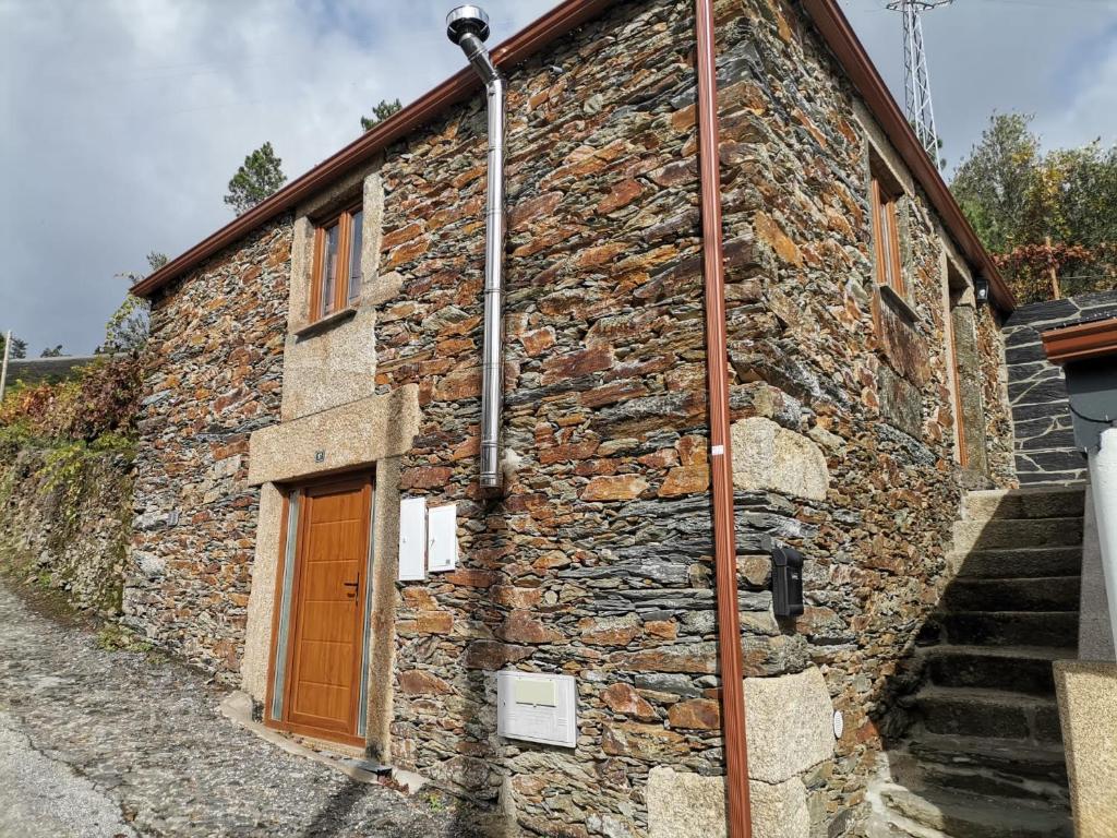 un edificio de piedra con una puerta marrón y escaleras en "Casa do Avô Armindo" Mountain Experience en Vila Real