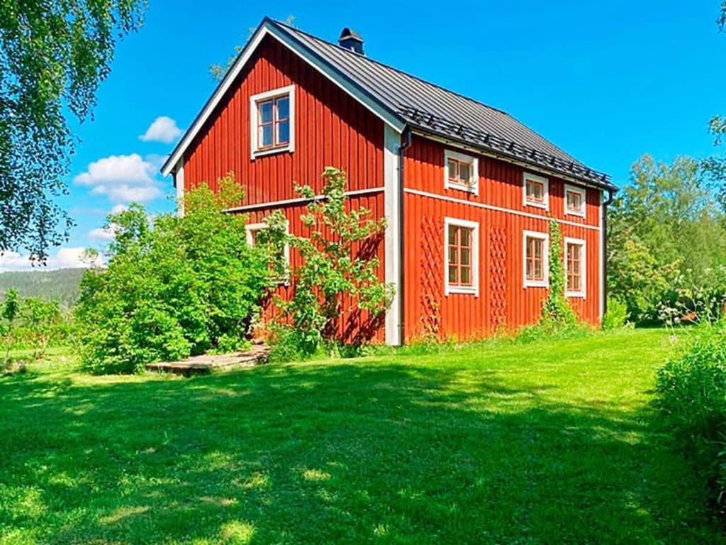 Nordingrå的住宿－Holiday home NORDINGRÅ，红谷仓,位于郁郁葱葱的绿色田野上