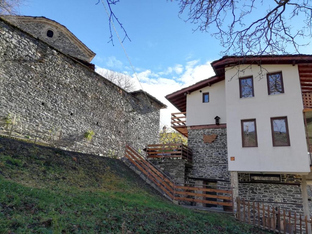 a white house next to a stone wall at GUEST HOUSE ELENA in Kosovo