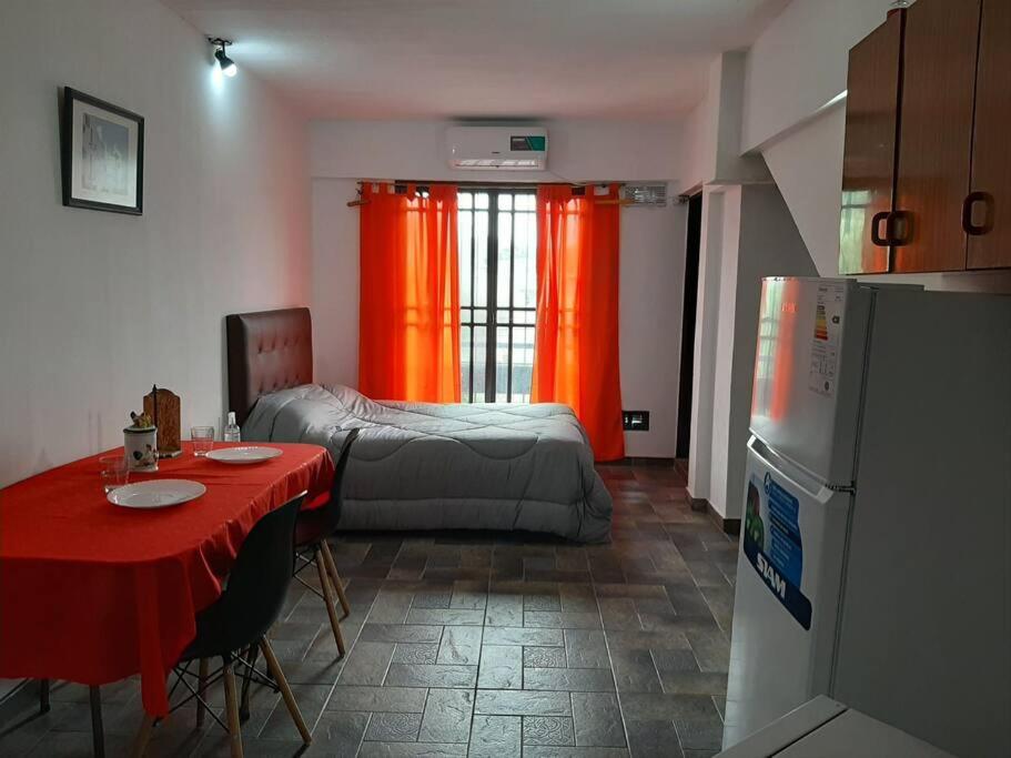 a kitchen with a table and a bed and a refrigerator at Alquiler Temporario Azcuénaga in Morón