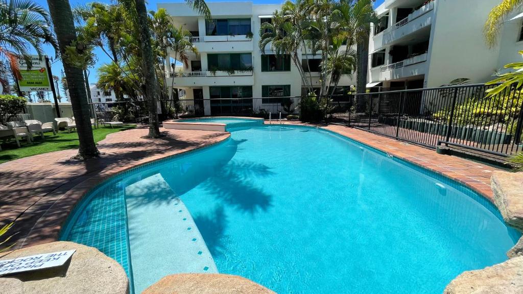 a large blue swimming pool in front of a building at Headland Gardens Holiday Apartments in Alexandra Headland