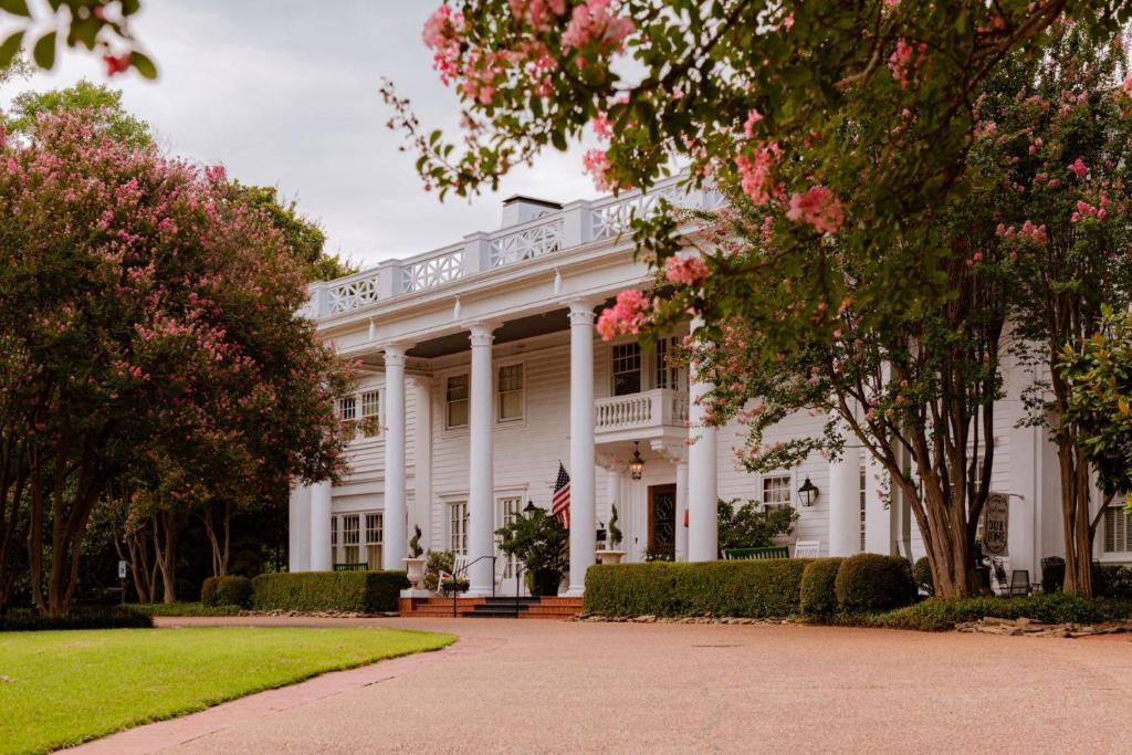 a white house with trees and pink flowers at Fairview Inn in Jackson