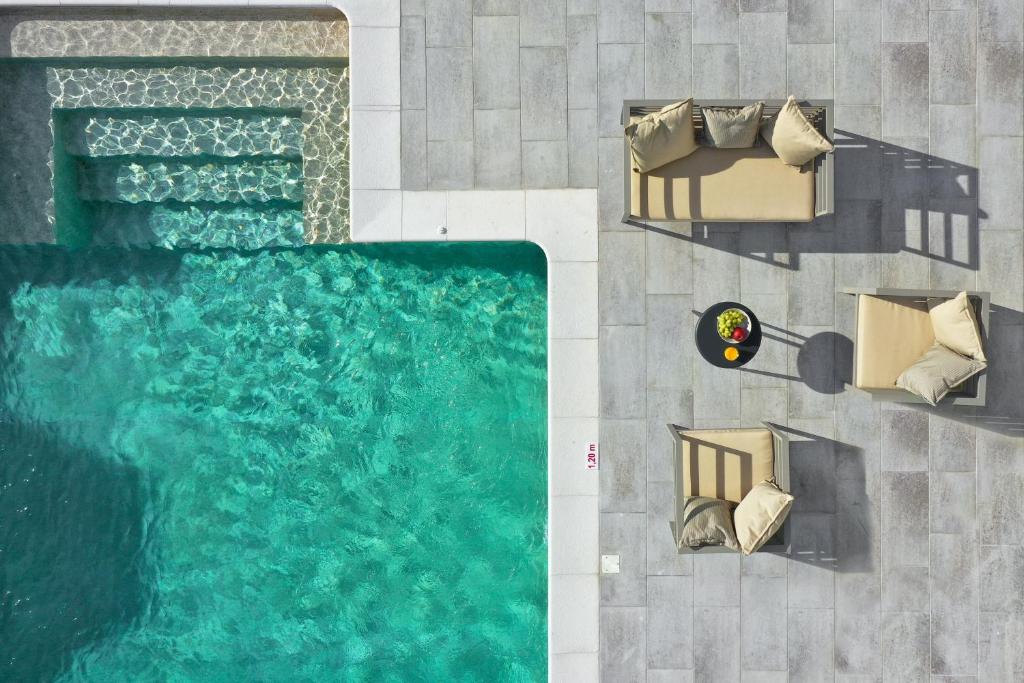 una vista sul soffitto di una piscina con sedie e tavoli di Pantheon Luxury Villas Rhodes Island a Afantou