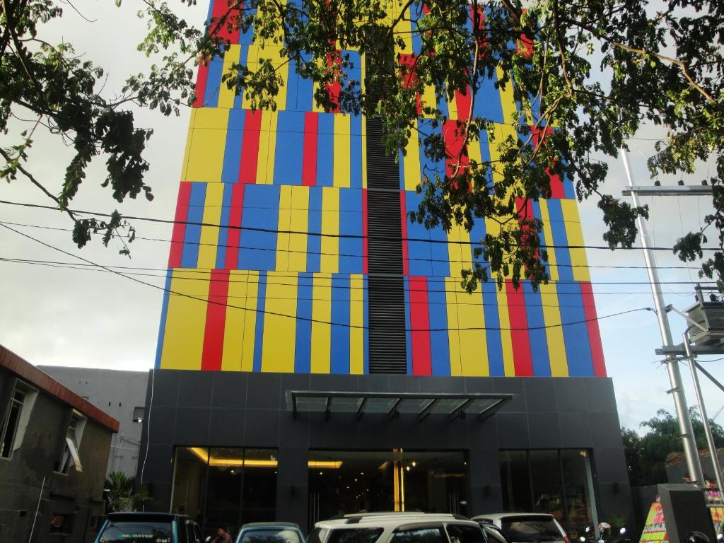 een kleurrijk gebouw met auto's geparkeerd voor het bij Top Hotel Manado by Gran Puri in Manado