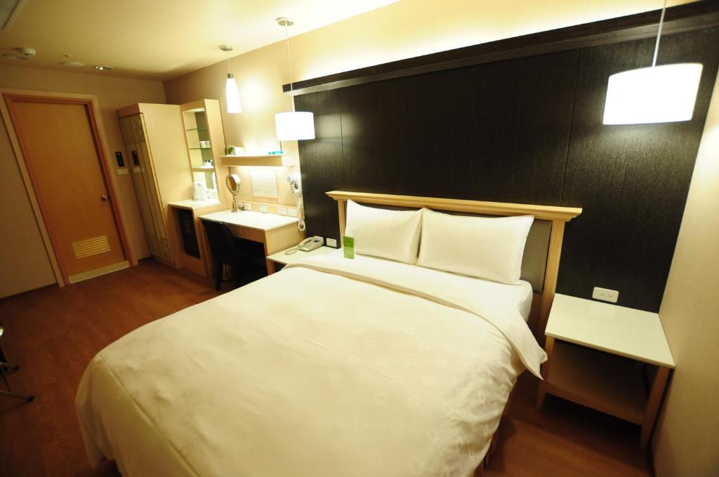 a hotel room with a large bed and a bathroom at Kindness Hotel - Kaohsiung Main Station in Kaohsiung