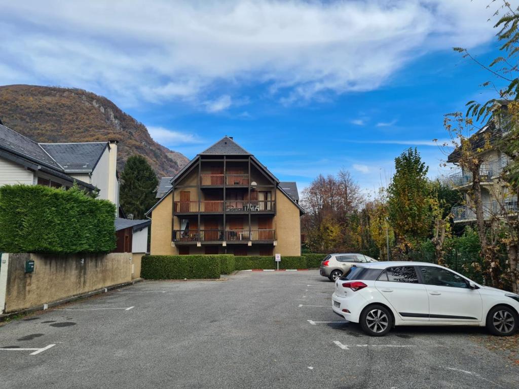 un coche blanco estacionado en un estacionamiento frente a un edificio en Très joli appartement 4-6 personnes dans Luchon en Luchon