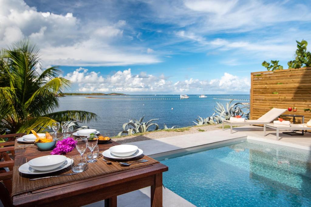 uma villa com uma piscina e uma mesa com vista em EAST KEYS - East Lagoon Suites em Le François